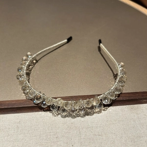 Détail des perles de cristal facettées sur un serre-tête fin en métal argenté brillant