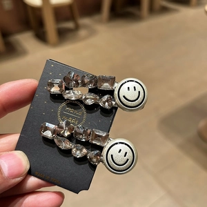 Detailed macro view of two silver rhinestone hairpins with crystal flowers and a smiley face