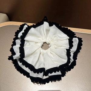 Détail d'un chouchou géant noir et blanc en organza avec bordure en velours chic