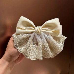 Detailed close-up of cream satin bow hair clip with shimmering glitter lace texture