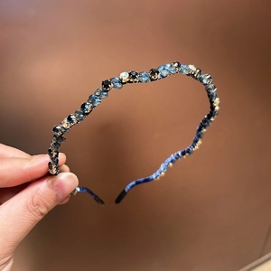 Detailansicht handgefertigter Kristall-Strasssteine und Goldperlen auf blauem Stirnband