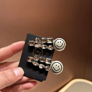 Detailed macro view of two Korean-style silver clips with sparkling crystals and smiley faces