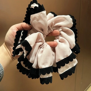 Détail d'un grand chouchou en mousseline rose avec bordure en velours noir