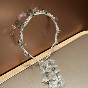 Macro detail of French style floral headband with blue crystals and long tassel charms