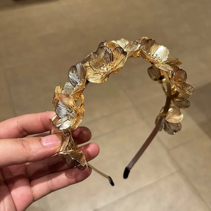 Detailed close-up of golden alloy floral headband with rhinestones and protective silicone tips