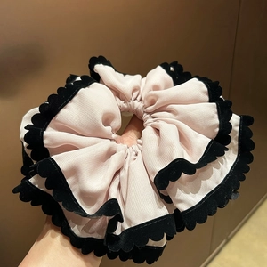 Détail d'un chouchou en mousseline rose avec plis superposés et bordure en velours noir