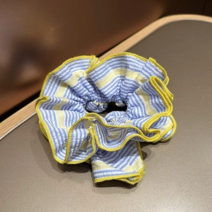 Détail de la texture rayée en seersucker et de la bordure jaune sur le chouchou en tissu