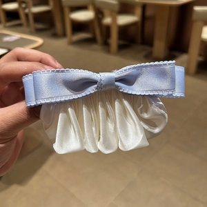 Détail de la pince à cheveux noeud en satin bleu clair avec tissu plissé crème chic
