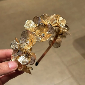 Detail of golden floral headband with sparkling crystals and brushed metal petals