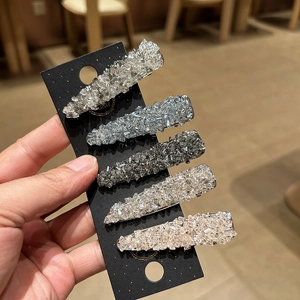 Detail showing five sparkling rhinestone hair clips in various colors on a display card