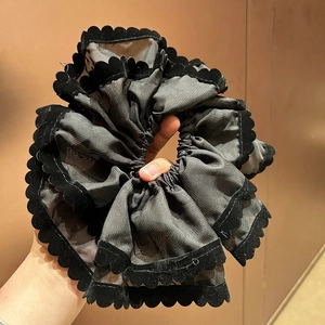 Gros plan d'un chouchou en maille double couche avec élégants bords festonnés en velours noir