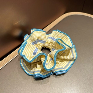Détail du chouchou en tissu rayé avec rayures jaunes et bords surpiqués bleus