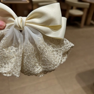 Detail of French chic satin bow hair clip with golden embroidery lace texture