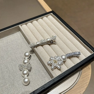 Nahaufnahme von drei eleganten Perlen- und Kristall-Haarspangen auf einem Samttablett