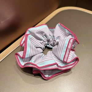 Détail d'un chouchou rayé rose et bleu montrant la couture fine et la texture du tissu