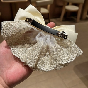Detail of large satin bow hair clip with lace trim and secure black metal spring clip