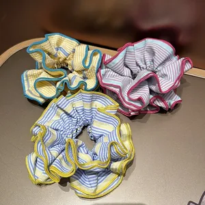 Détail de trois chouchous en tissu rayé avec des bords à volants contrastés élégants