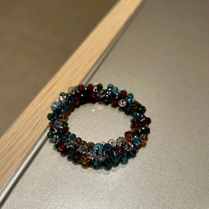 Detailed macro view of colorful faceted crystal beaded rings in navy, emerald, and amber