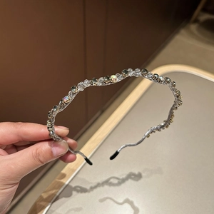Detail eines gewellten Kristallstirnbands mit grauem Stoff und bunten Strasssteinen