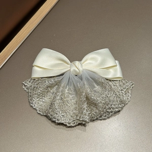 Detailed close-up of French satin bow hairclip with intricate gold lace and mesh textures