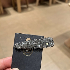 Close-up of a sparkling silver rhinestone hair clip mounted on a black gift card