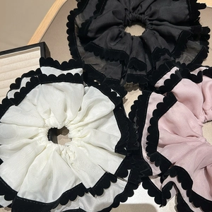 Détail de chouchous en mousseline à volants superposés avec bordures floquées noires en trois tons