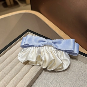 Gros plan sur la barrette nœud bleu clair élégante avec plis en satin blanc sur plateau