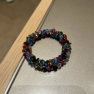 Close-up of high-end colorful faceted crystal beads and braided elastic hair tie texture