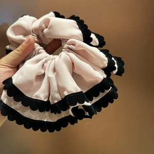 Détails du chouchou en mousseline rose clair avec bords festonnés en velours noir