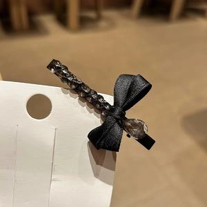 Détail d'une barrette à nœud en velours noir avec strass gris et goutte en cristal