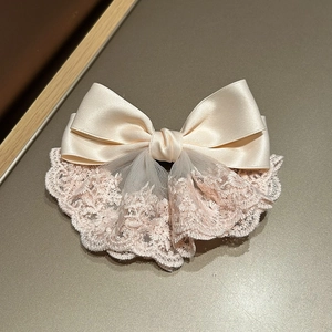 Detail of pink satin bow hair clip featuring intricate floral lace and silk ribbon texture