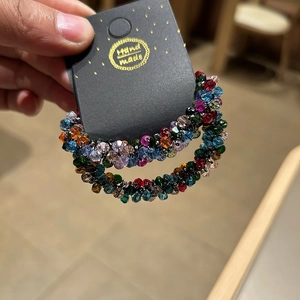Close-up of handmade multi-color faceted crystal bead hoop earrings on a black display card