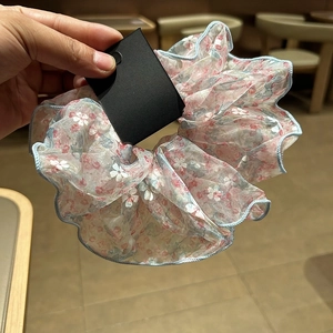 Détail d'un chouchou floral en mousseline avec fleurs roses et bordure bleue