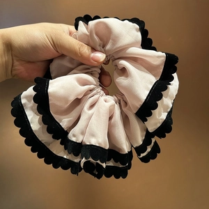 Détail de chouchou en organza rose multicouche avec bordure ondulée en velours noir