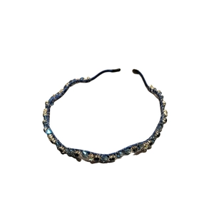 Eleganter wellenförmiger Haarreif mit funkelnden blauen und schwarzen Kristallen auf Weiß