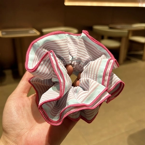 Détail d'un chouchou en tissu à rayures bleues et roses avec texture fine et coutures rouges