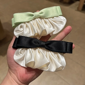 Détail de pinces à cheveux à nœud en satin vert et noir avec bords plissés élégants