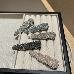 Detail of five rhinestone duckbill hair clips in assorted colors on a jewelry tray