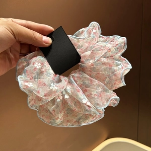 Détail d'un chouchou en organza à fleurs roses avec des bords surjetés bleu clair