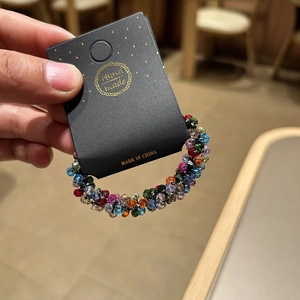 Detail of colorful faceted crystal bead elastic hair tie on a black handmade card