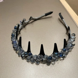 Détail d'un serre-tête en tissu gris avec pointes punk noires et perles en cristal bleu
