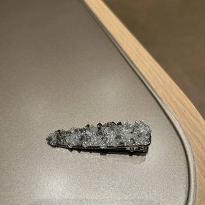 Detailed view of a silver triangular hair clip with faceted grey and clear crystals