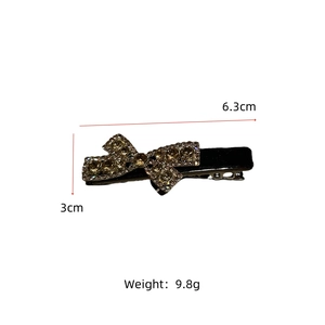 Detail view of a black velvet bow hair clip with champagne rhinestones and size dimensions