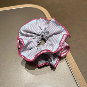 Chouchou en tissu à rayures roses et bleu clair avec une texture douce et délicate