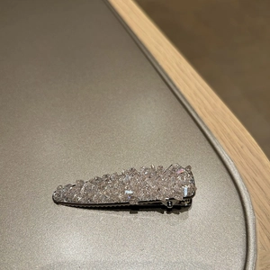 Close-up of a silver metal duckbill hair clip with shimmering rows of rhinestones