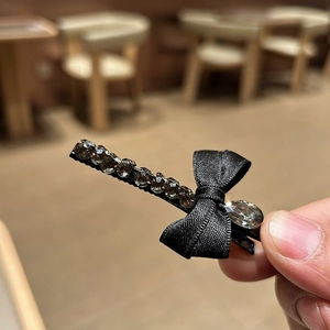 Détail d'une barrette noeud en velours noir avec des strass de luxe et une base en métal