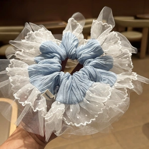 Détail d'un chouchou bleu avec dentelle blanche à pois et étiquette faite à la main