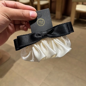 Vue détaillée du nœud en satin noir fait main avec des volants plissés ivoire