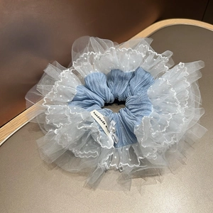 Gros plan du chouchou en dentelle bleue avec résille blanche, pois et nœud en perle élégant