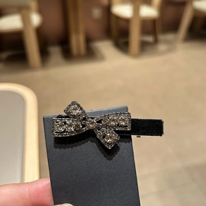 Elegant black velvet bow hair clip with sparkling rhinestones on a display card